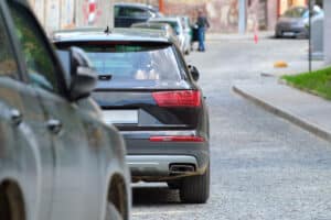 city traffic with cars parked in line on street side.